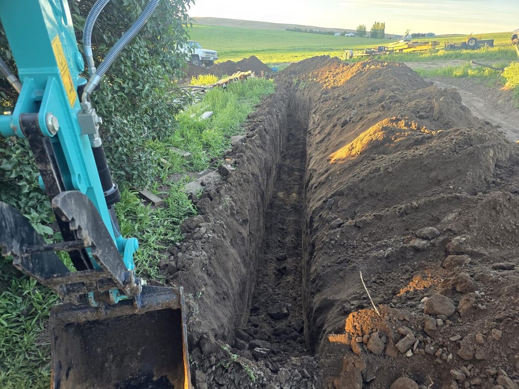Mini excavator digging an irrigation trench