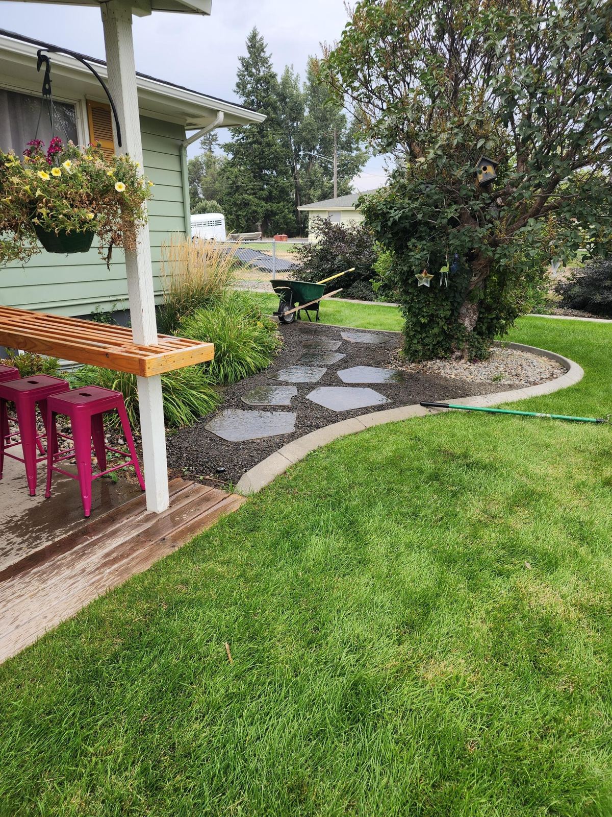 Backyard patio with a wood bench, stepping-stone path and fresh lawn