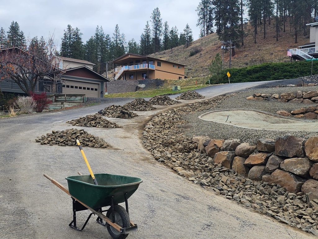 Rock retaining wall and gravel driveway along a hillside home